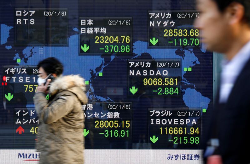 © Reuters. People walk past an electronic display showing world markets indices outside a brokerage in Tokyo