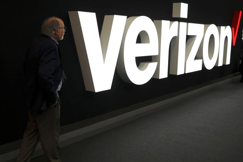 © Reuters. FILE PHOTO:  A man stands next to the logo of Verizon at the Mobile World Congress in Barcelona