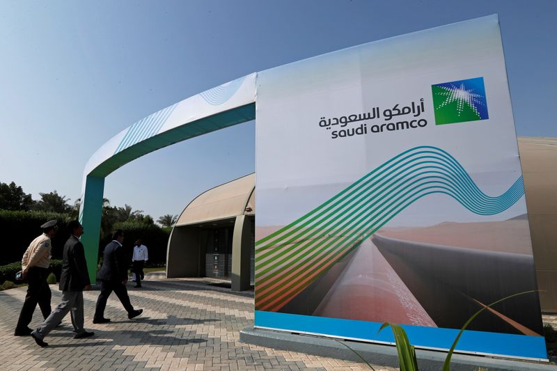 © Reuters. Logo of Aramco is seen as security personnel walk before the start of a press conference by Aramco at the Plaza Conference Center in Dhahran