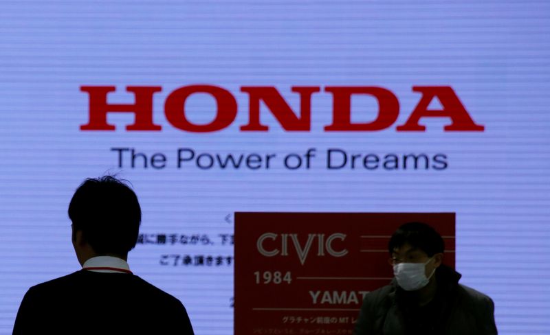 © Reuters. Men are silhouetted against a logo of Honda Motor at the company's showroom in Tokyo