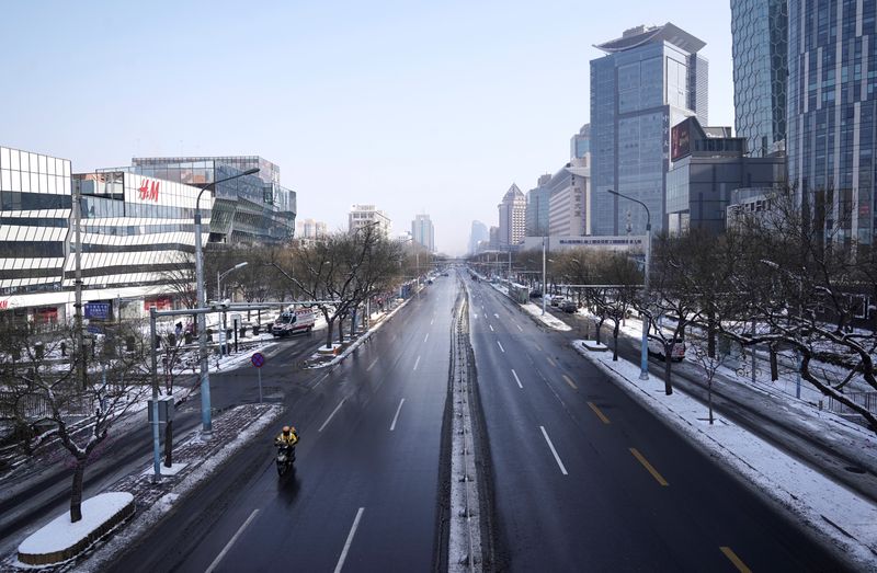 © Reuters. El repartidor viaja en una calle en el área de Sanlitun, cuando el país se ve afectado por un brote del nuevo coronavirus, en Beijing