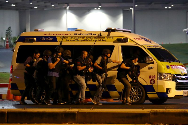 © Reuters. Thailand security forces take cover behind an ambulance as they chase a shooter hidden in a shopping mall after a mass shooting in front of the Terminal 21, in Nakhon Ratchasima, Thailand