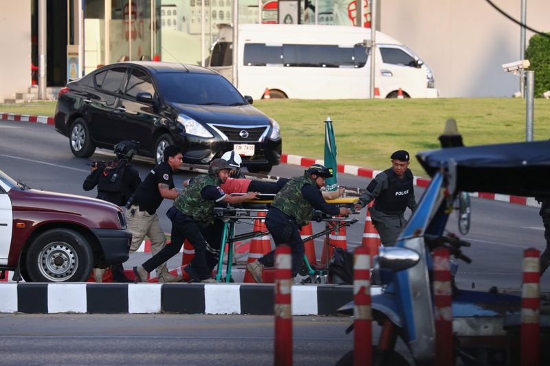 © Reuters. Thai security forces evacuate people who were stranded inside the Terminal 21 shopping mall following a gun battle, to try to stop a soldier on a rampage after a mass shooting, Nakhon Ratchasima