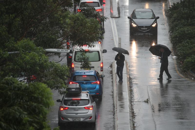 © Reuters. Pedestrians brave strong wind and rain in Sydney