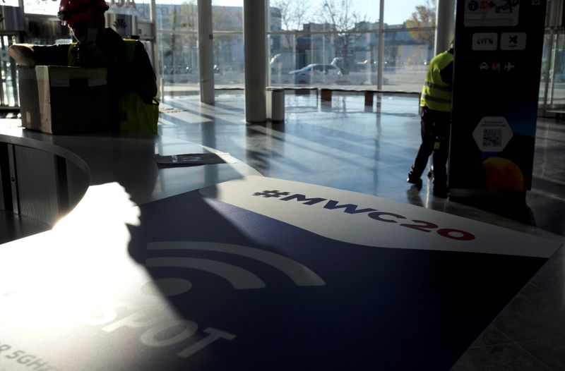© Reuters. Employees work next to a banner with information of MWC20 in Barcelona