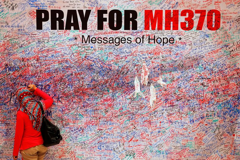 © Reuters. FILE PHOTO: A woman leaves message of support and hope for passengers of missing Malaysia Airlines MH370 in central Kuala Lumpur