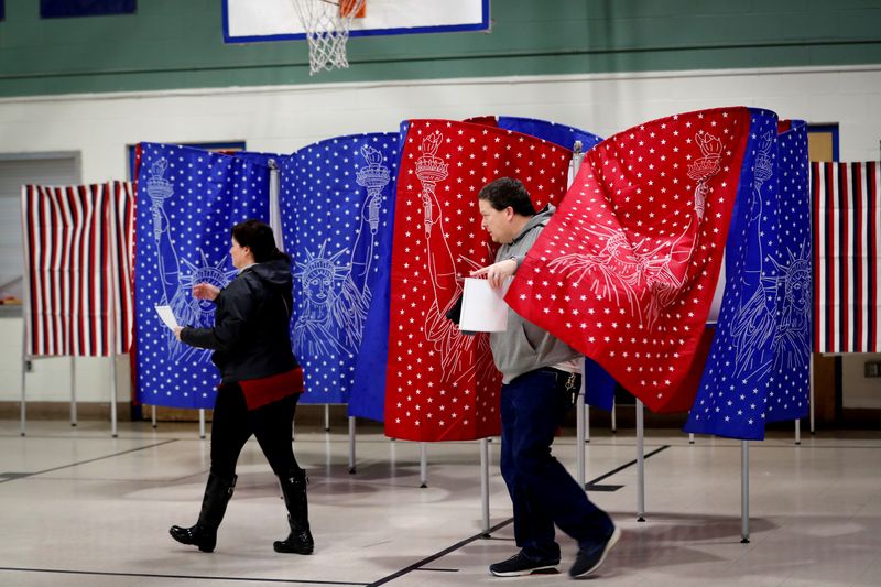 © Reuters. Voters carry ballots from voting booths while voting in the New Hampshire U.S. presidential primary election in Manchester