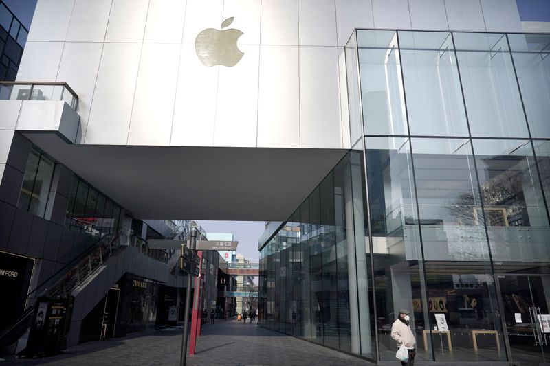 © Reuters. Man wearing a face mask walks past a closed Apple store at Sanlitun in Beijing