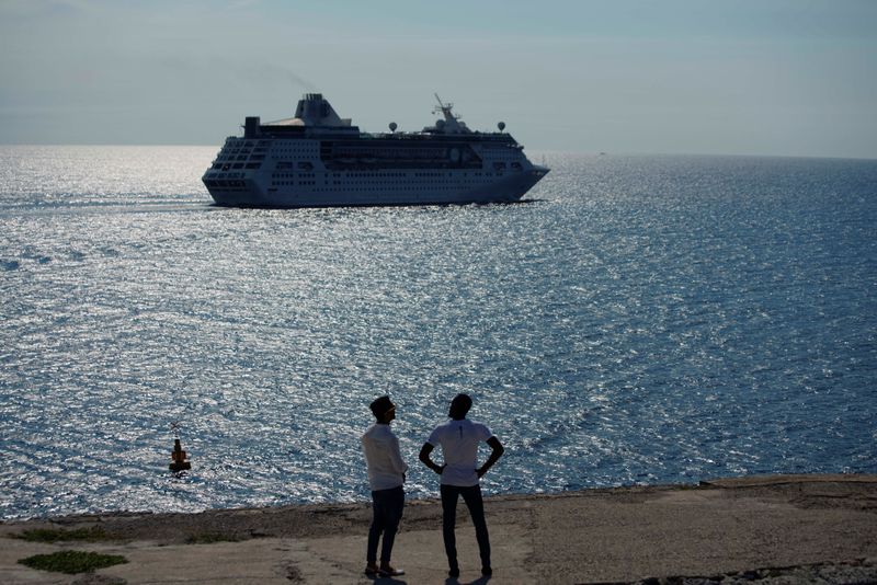 © Reuters. Men watch the cruise ship MS Empress of the Seas, operated by Royal Caribbean International, as it leaves the bay of Havana