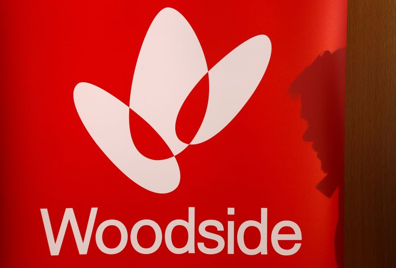 © Reuters. FILE PHOTO: The shadow of a man is cast onto a poster displaying the logo for Woodside Petroleum, Australia's top independent oil and gas company, at a briefing for investors in Sydney,