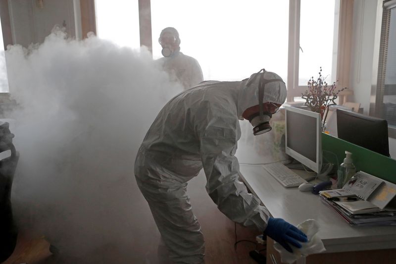 © Reuters. FILE PHOTO: Workers with sanitising equipment disinfect an office following an outbreak of coronavirus in the country, in Shanghai