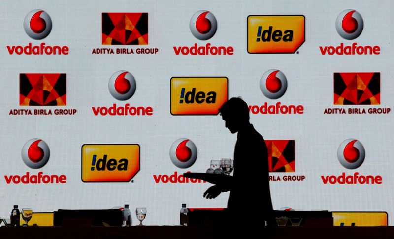 © Reuters. FILE PHOTO: A hotel employee clears a table after Vodafone Group and Idea Cellular news conference in Mumbai