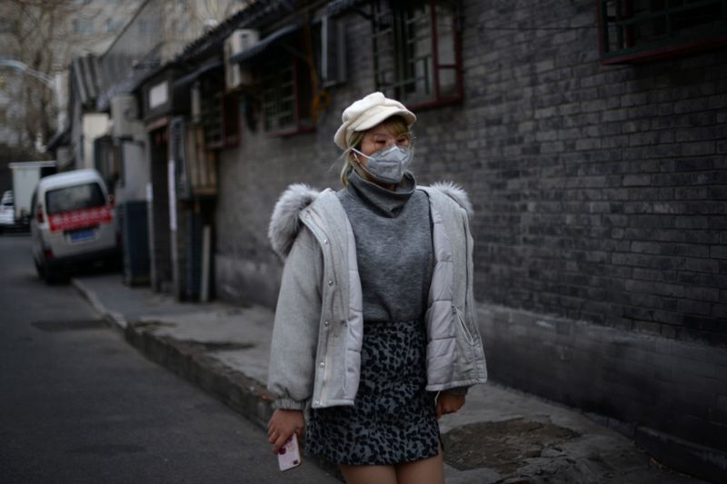 © Reuters. Woman wearing a face mask walks at a hutong, as the country is hit by an outbreak of the novel coronavirus, in Beijing