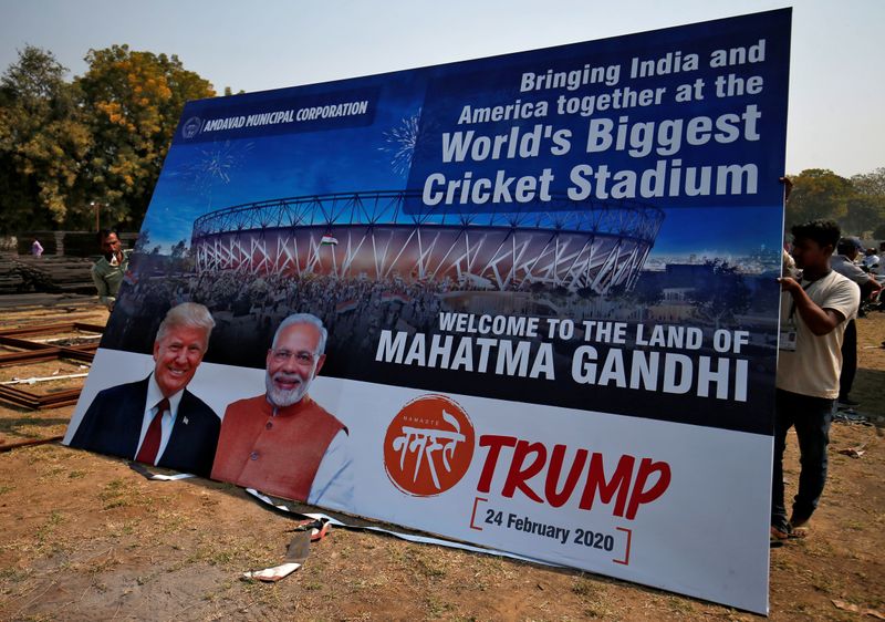 © Reuters. Workers prepare a hoarding with the images of the U.S. President Donald Trump and India's Prime Minister Narendra Modi ahead of Trump's visit, on the outskirts of Ahmedabad