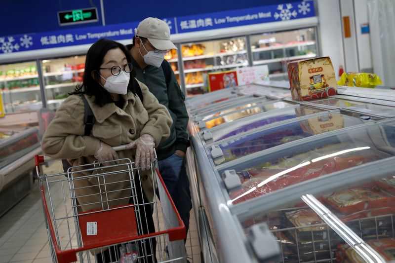 © Reuters. Las personas que usan mascarillas buscan productos en un supermercado, ya que el país se ve afectado por un brote del nuevo coronavirus, en Beijing