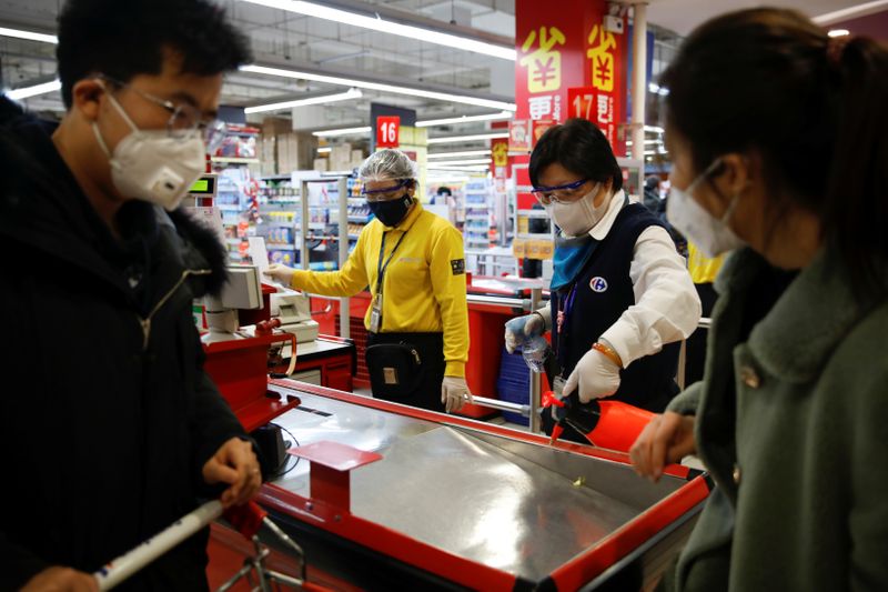 © Reuters. A staff member wearing a face mask sanitizes a cashier counter at a supermarket, as the country is hit by an outbreak of the new coronavirus, in Beijing