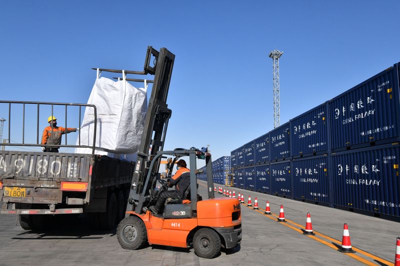 © Reuters. Workers wearing face masks load cargo to a truck next to containers at a railway cargo terminal, as the country is hit by an outbreak of the novel coronavirus, in Yinchuan