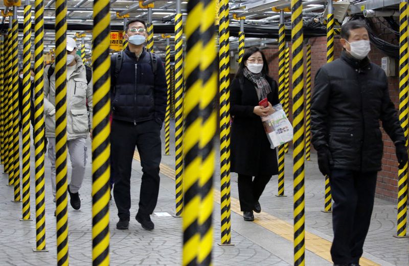© Reuters. People wearing masks as a preventive measure against the coronavirus walk at a subway station in Seoul