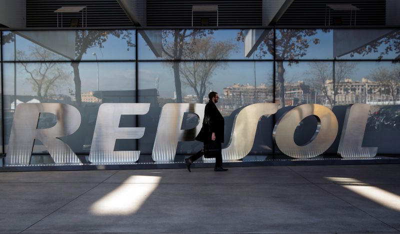 © Reuters. FOTO DE ARCHIVO: Un hombre pasa junto al logotipo de la empresa en la sede de Repsol en Madrid el 16 de diciembre de 2014