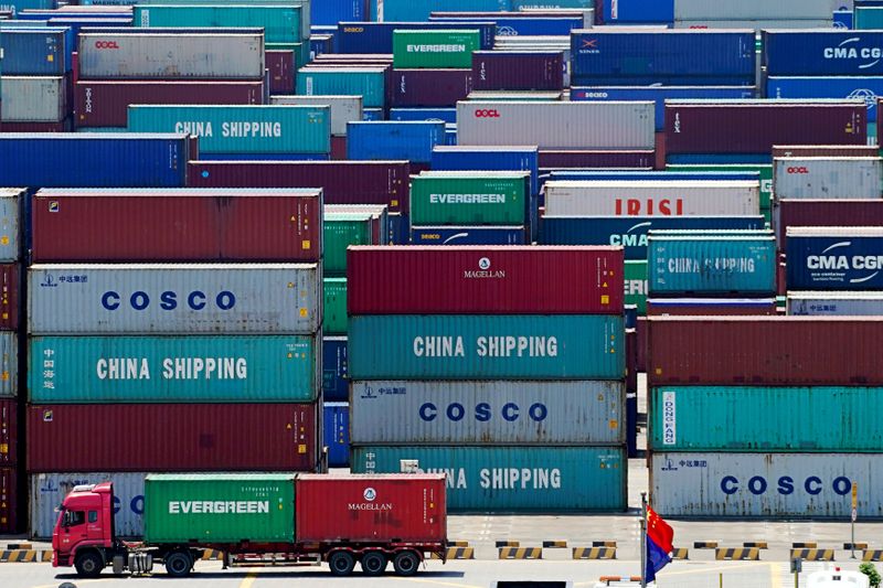 © Reuters. FILE PHOTO: Truck carrying containers are seen near a Chinese flag at the Yangshan Deep Water Port in Shanghai