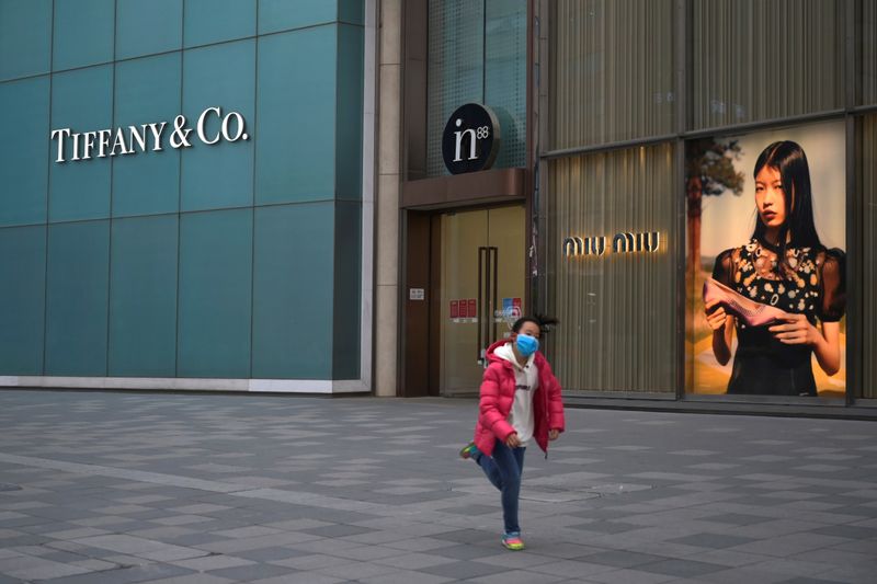 © Reuters. Child wearing a face mask runs past stores of Tiffany & Co and Miu Miu, as the country is hit by an outbreak of the novel coronavirus, in Beijing