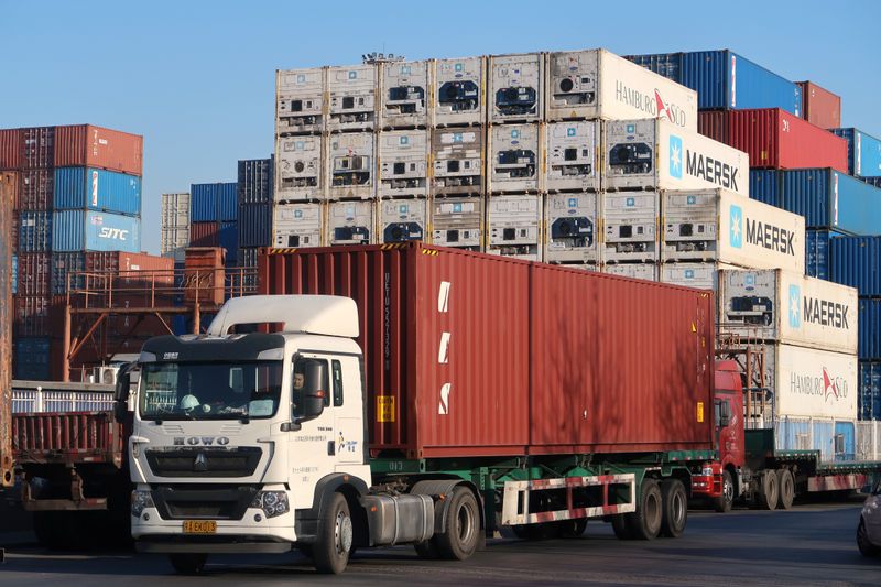 © Reuters. Trabajador conduce un camión con un contenedor en un centro logístico cerca del puerto de Tianjin