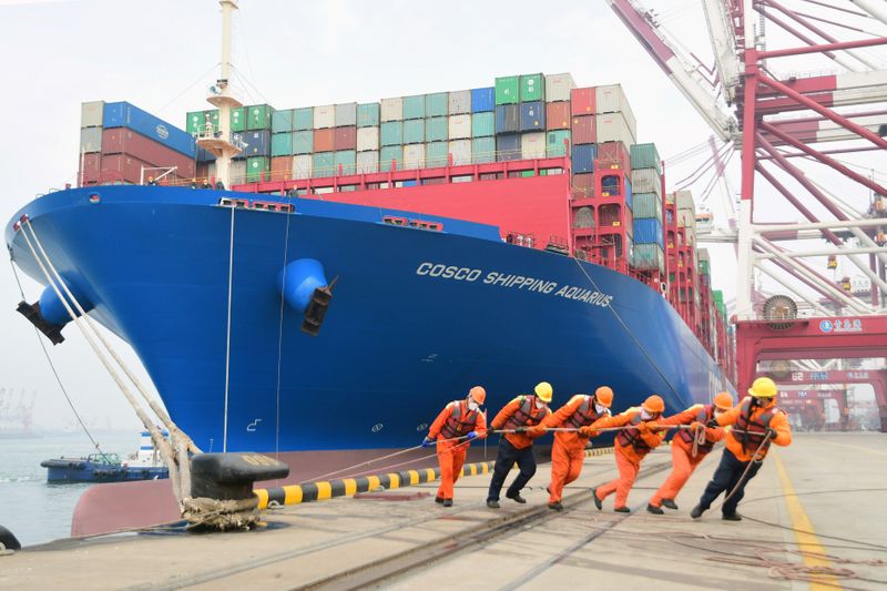 © Reuters. FILE PHOTO:  Workers wearing face masks rope a container ship at a port in Qingdao