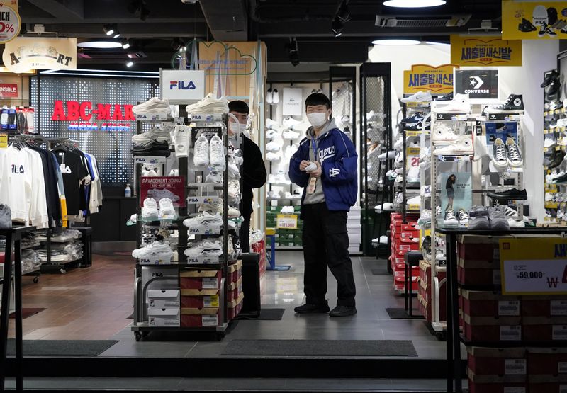 © Reuters. Shopkeepers wearing masks to prevent contracting the coronavirus wait for a customer at Dongseong-ro shopping street in central Daegu