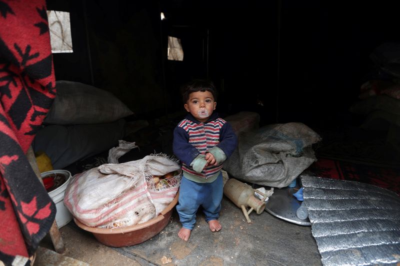 © Reuters. Internally displaced child looks out from a tent in Azaz