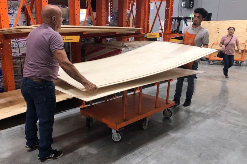 © Reuters. Men lift a sheet of plywood at a Home Depot store ahead of the arrival of Hurricane Dorian in Miami