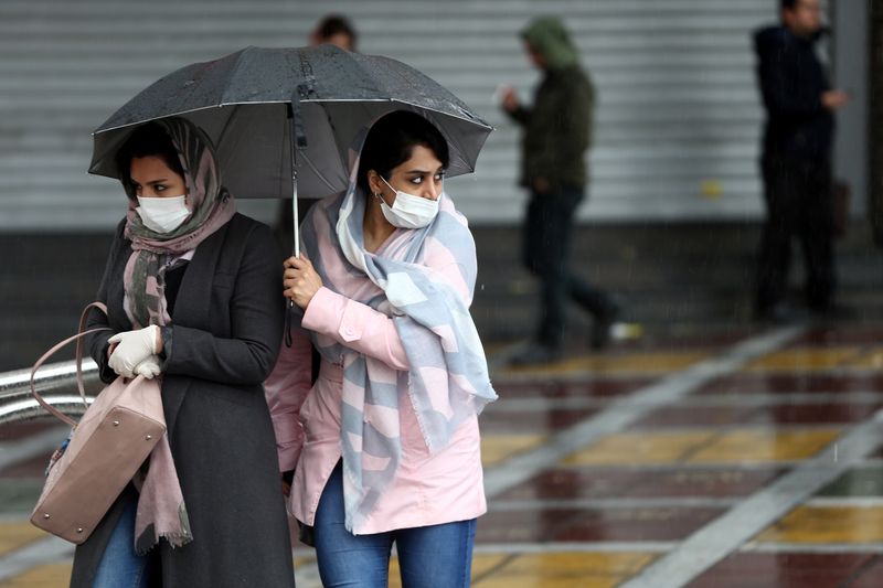 © Reuters. Iranian women wear protective masks to prevent contracting coronavirus, as they walk in the street in Tehran