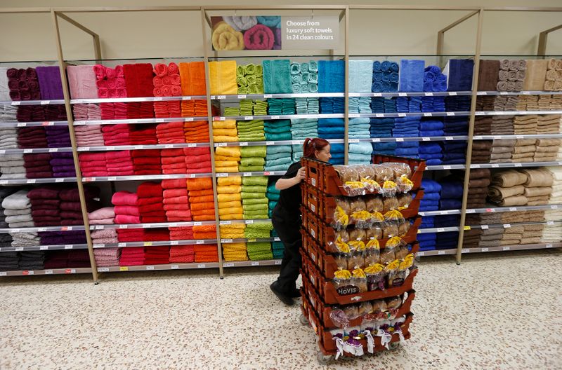 © Reuters. A bakery employee pushes a cart with loaves of bread past a towel display at a Tesco Extra supermarket in Watford, north of London