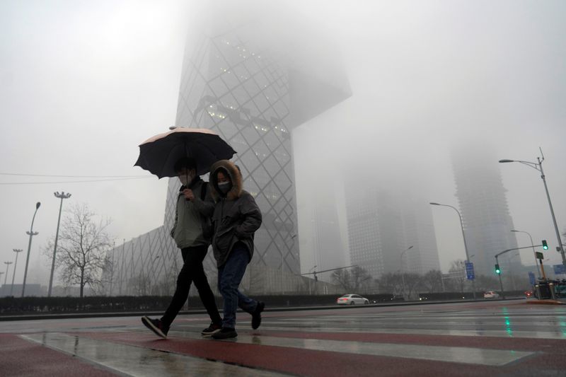 © Reuters. Pedestrians wearing face masks walk amid rainfall at the Central Business District, as the country is hit by a novel coronavirus outbreak, in Beijing