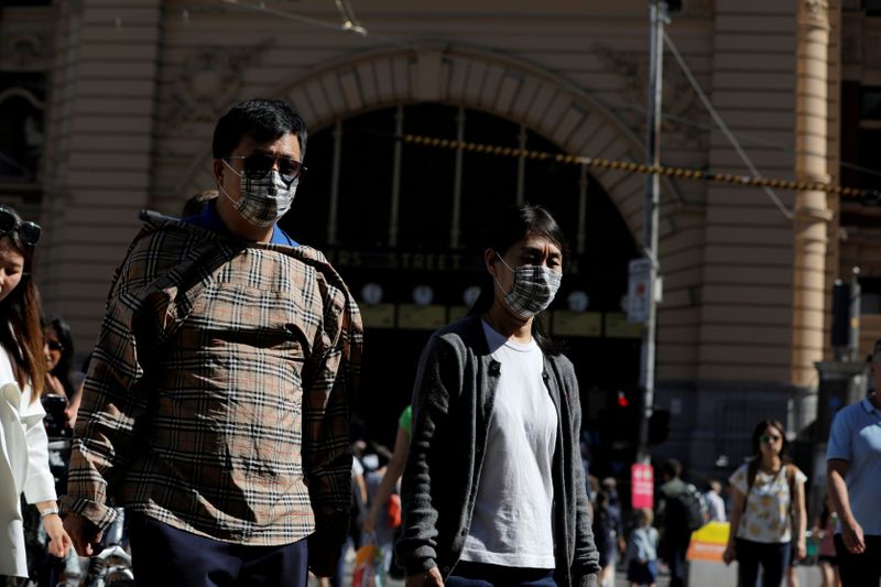 © Reuters. FOTO DE ARCHIVO: Las personas con máscaras faciales caminan por la estación de Flinders Street después de que se confirmaran casos de coronavirus en Melbourne