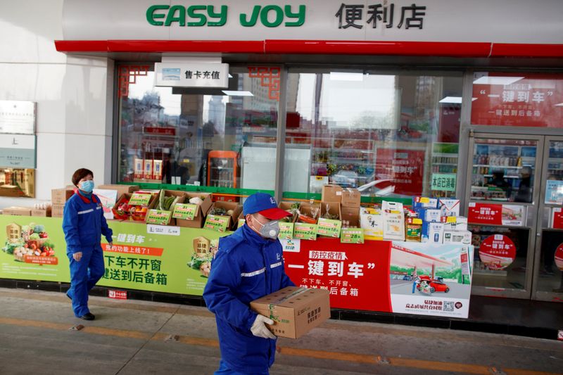 © Reuters. FILE PHOTO: A pump attendant carries a box of groceriees into a car at a Sinopec gas station in Beijing where customers can buy supplies while they refuel