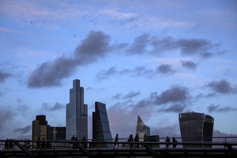 © Reuters. FILE PHOTO: Pedestrians walk over the Millennium Bridge in view of skyscrapers in the financial district in London
