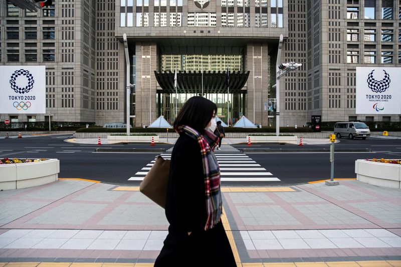 © Reuters. FILE PHOTO: A woman wearing a protective face mask, following an outbreak of the coronavirus, walks past banners of the upcoming Tokyo 2020 Olympic and Paralympic Games outside the Tokyo Metropolitan Government building in Tokyo