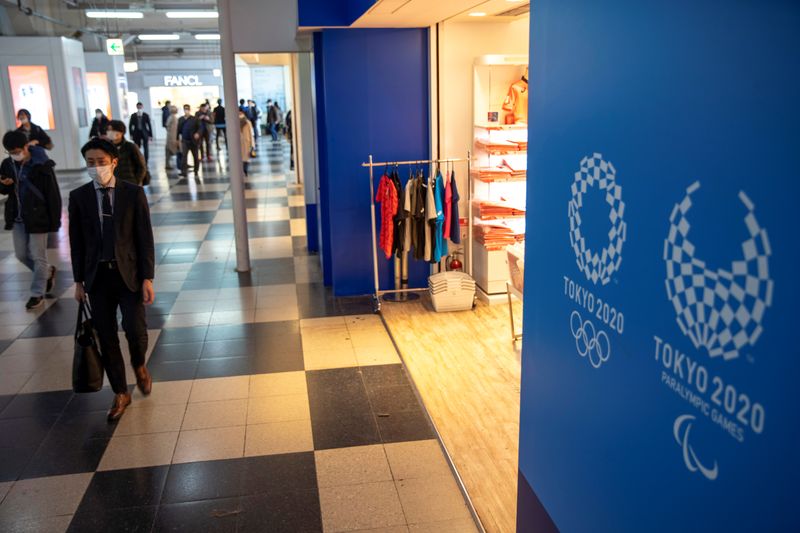 © Reuters. A man wearing a protective face mask, following the outbreak of the coronavirus, walks past Tokyo Olympic 2020 souvenir shop at Shibuya shopping district in Tokyo