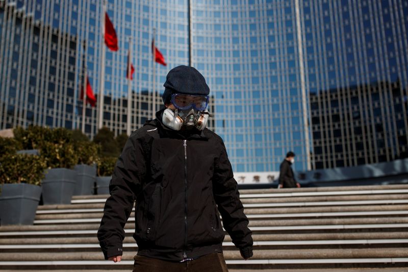 © Reuters. A man wearing a mask walks near office buildings in Beijing