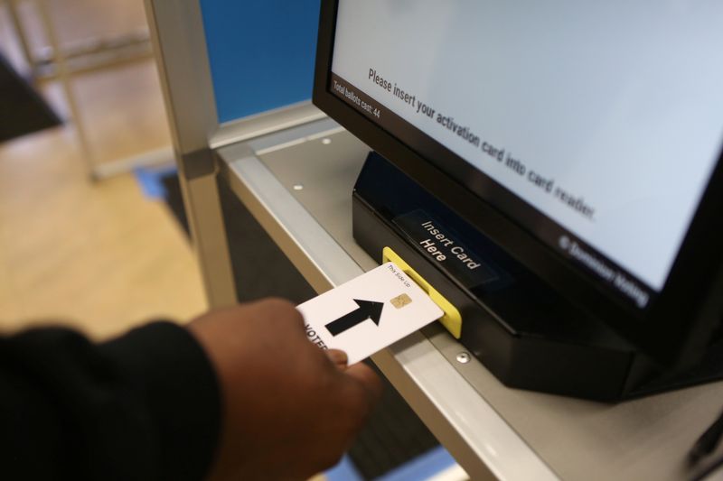 © Reuters. A man inserts his voter card into a touchscreen voting machine at a voting center at Oak Park Community Center for the presidential primaries on Super Tuesday in Sacramento