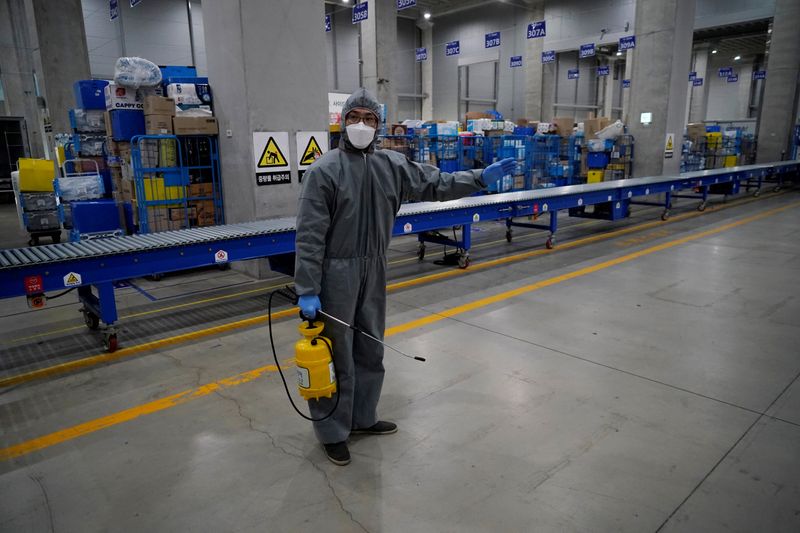 © Reuters. A worker in a protective gear sanitizes packages before leaving to deliver them in Incheon