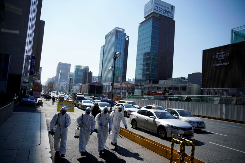 © Reuters. South Korean soldiers in protective gear sanitize a street in Seoul