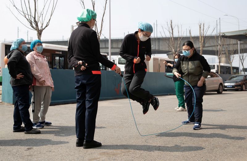 © Reuters. Medical workers wearing face masks jump rope as they take break outside hotel where they stay, in Wuhan