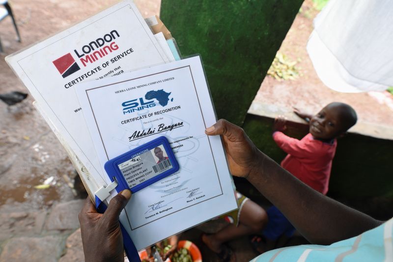 © Reuters. Former mine worker Abdulai Bangura shows his employment documents from SL Mining, Timis Mining and London Mining,during am interview with Reuters journalist at his home at Labor Camp community in Lunsar