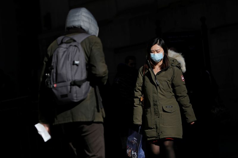 © Reuters. A woman in a face mask walks in the downtown area of Manhattan, New York City, after further cases of coronavirus were confirmed in New York