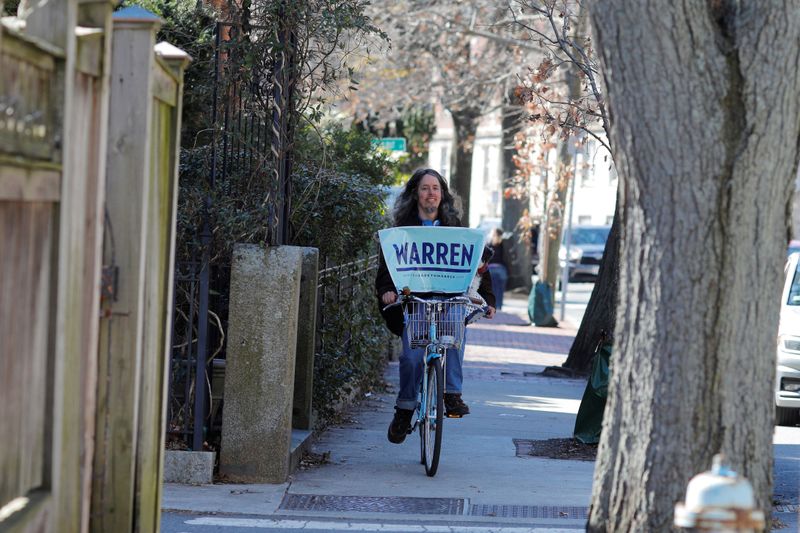 © Reuters. A supporter rides a bike after Democratic U.S. presidential candidate Warren spoke to reporters  in Cambridge