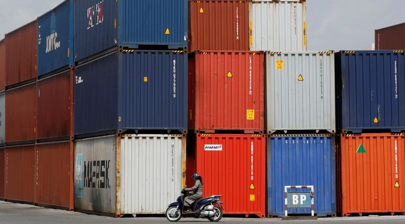 © Reuters. FILE PHOTO: Woman rides a motorcycle as she passes containers at Hai Phong port