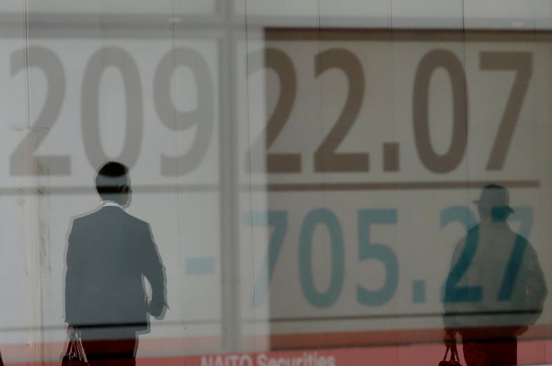 © Reuters. FILE PHOTO: Men are reflected on an electronic board showing the Nikkei stock index outside a brokerage in Tokyo