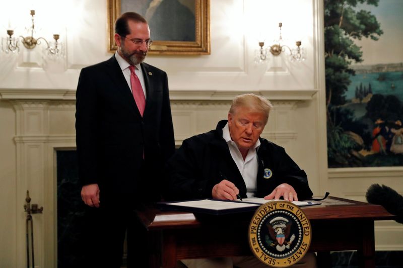 © Reuters. U.S. President Donald Trump accompanied by Health and HHS Secretary Alex Azar,  signs the Congressional funding bill for coronavirus response at the White House in Washington