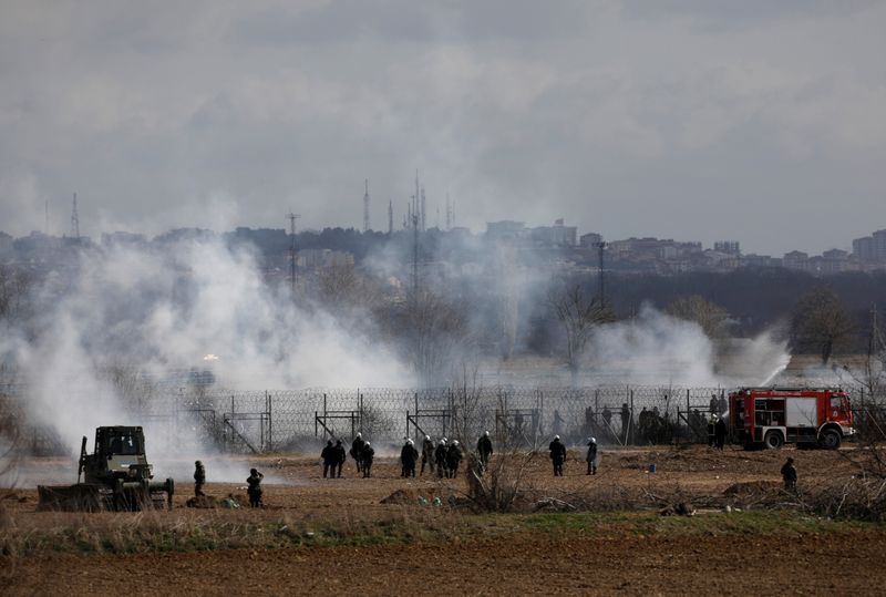 © Reuters. Soldados griegos y policías antidisturbios se encuentran entre nubes de gas lacrimógeno cerca del paso fronterizo de Pazarkule en Turquía, en Kastanies, Grecia